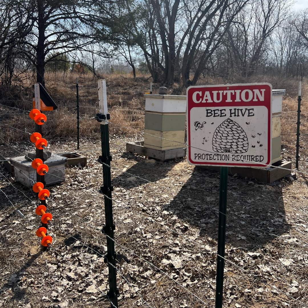 Bee boxes with a caution sign in front of them.